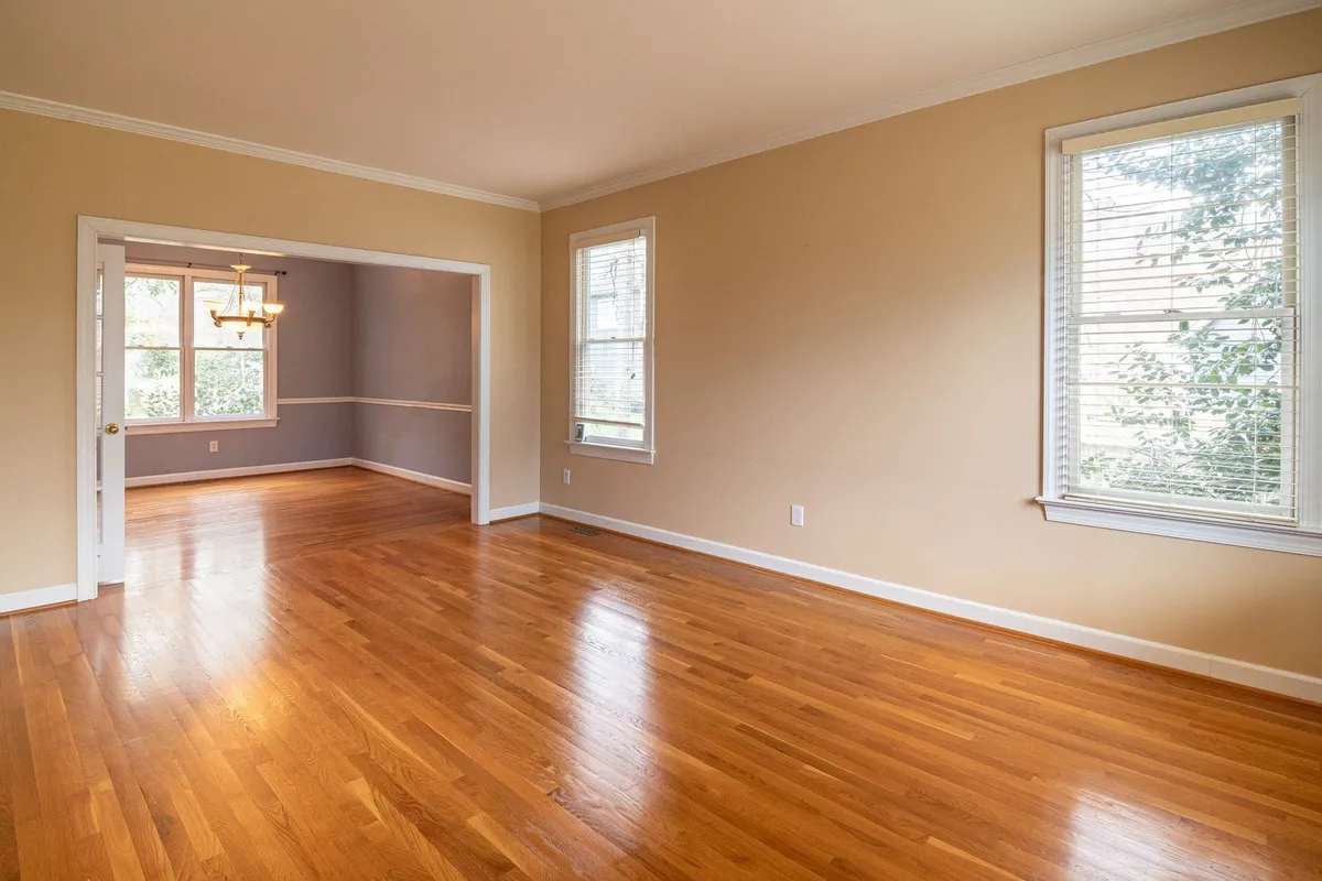 Bright empty room with wooden floors and large windows, perfect for showcasing the need for furniture removal.